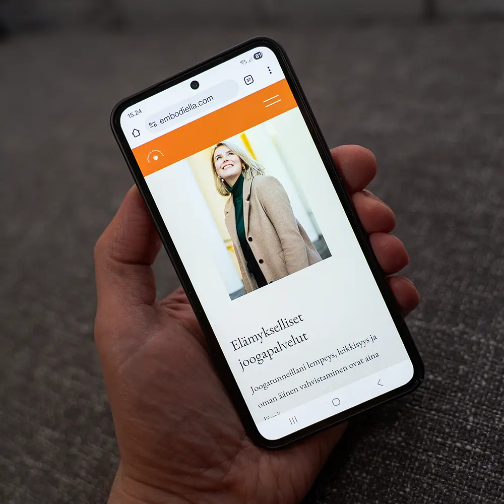 Henkilö pitelee puhelinta, jossa on auki Ellariina Raution sivusto Embodiella.com